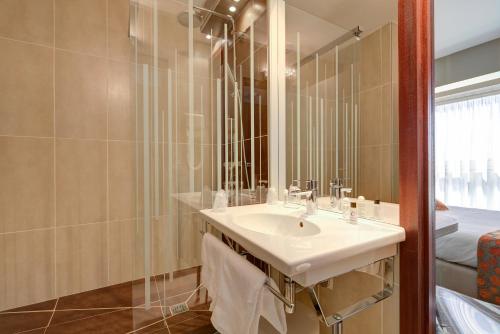 a bathroom with a sink and a mirror at Hôtel Le Nautic in Arcachon
