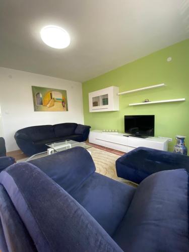 a living room with blue couches and a tv at Apartman “IVA” in Drvar