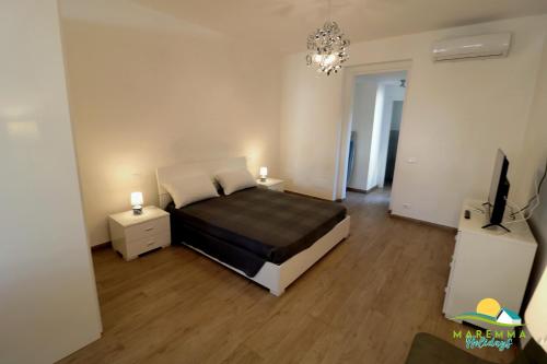 a bedroom with a bed and two night stands and a television at M.H Bovio Apartment in Follonica
