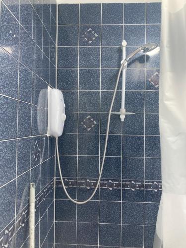 a blue tiled bathroom with a shower with a hose at HILLTOP PLACE Suites Near Doncaster RaceCourse in Doncaster