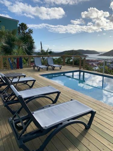 a deck with two chairs and a swimming pool at The Green Iguana Hotel in Charlotte Amalie