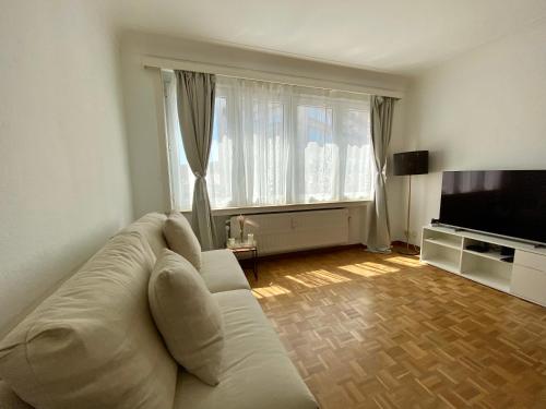 sala de estar con sofá blanco y TV en Cinquantenaire Appartement, en Bruselas