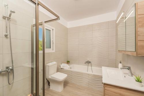 a bathroom with a toilet and a tub and a sink at Villa Hali Maris by Villa Plus in Plános