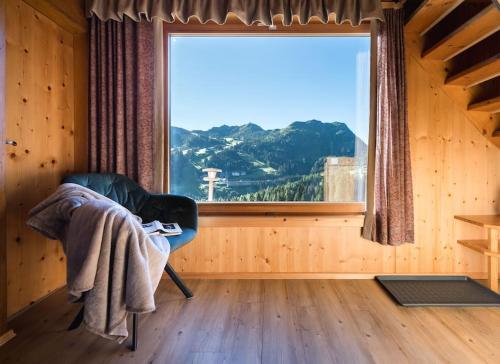 Zimmer mit einem Stuhl und einem großen Fenster in der Unterkunft Gemütliche Hütte in den Bergen in Sonnenalpe Nassfeld