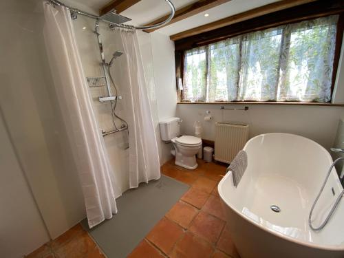baño con bañera, aseo y ventana en Brundish Suffolk Barn 2 Bed Idyllic 6 acres, en Wilby