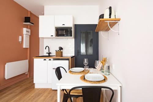 une petite cuisine avec une table et des chaises blanches dans l'établissement Les Studios du Parc Bordelais - Le Canelé, à Le Bouscat