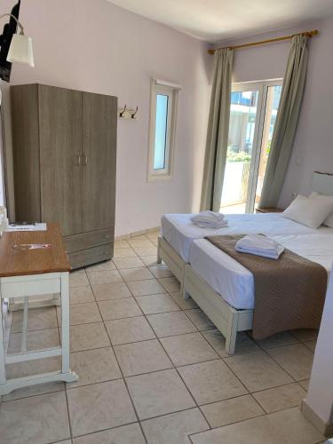 a bedroom with two beds and a wooden cabinet at Girogiali beach hotel - Adults only in Stalos