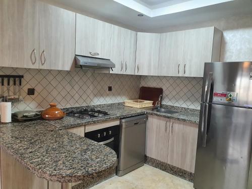 a kitchen with a stainless steel refrigerator and cabinets at Bel appartement à savannah beach sidi rahal in Sidi Rahal