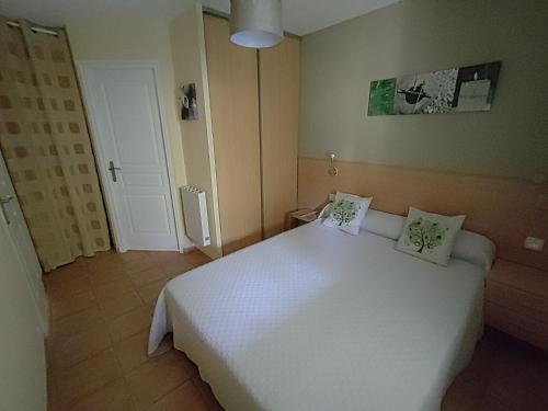 1 dormitorio con 1 cama blanca grande y 2 almohadas en Gîte à BELESTA en Ariège 09300 en Bélesta