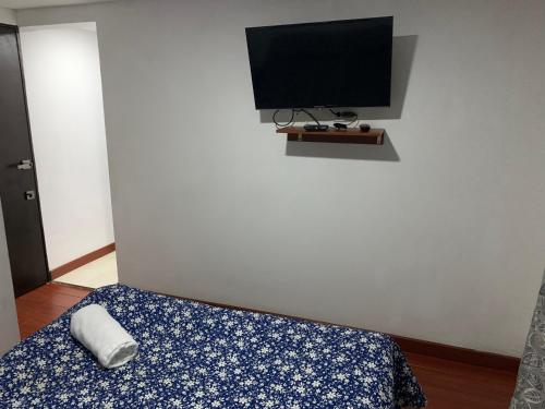 1 dormitorio con 1 cama y TV en la pared en Apartamento en el Norte de Bogota, en Bogotá