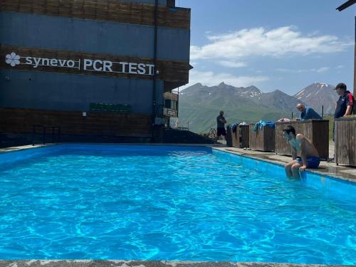 una mujer sentada en una piscina con montañas en el fondo en Twins apartment deluxe, new gudauri, en Gudauri