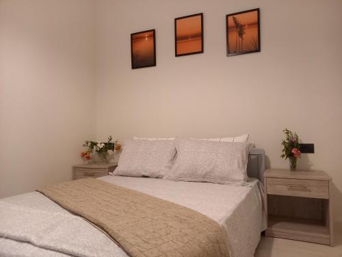 ein Schlafzimmer mit einem Bett und drei Bildern an der Wand in der Unterkunft Nebulous Apartment in Zakynthos