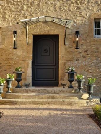 a stone building with a black door and stairs at La Petite Aiguebonne in Allex