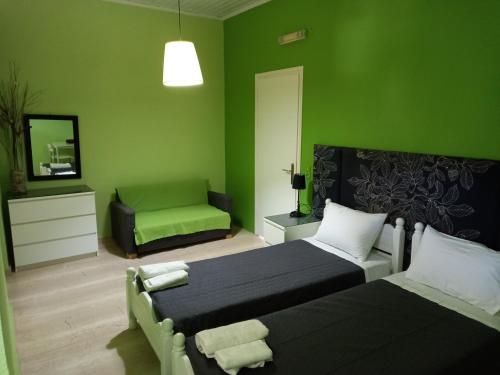 Un dormitorio verde con 2 camas y una silla en Maria's Studios, en Agios Georgios