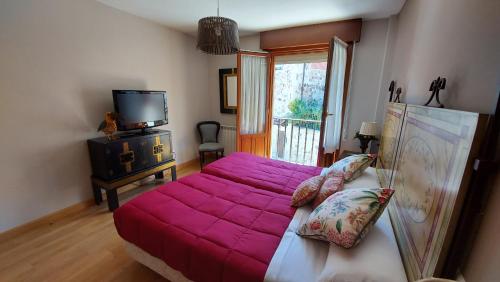 a bedroom with a large pink bed and a television at El Mirador de Molinos in Molinos de Duero