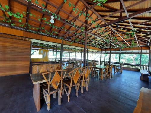 a restaurant with wooden tables and chairs and windows at HOTEL BESAR BULAN BARU - Senggigi in Senggigi 