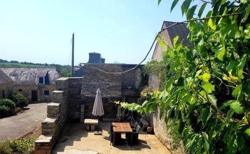 a patio with a table and an umbrella at Ti Fanch, maison proche de Quimper in Landudal