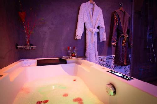 a purple bathroom with a bath tub with a robe at The Waterside Designer Waterfront Oasis Spa & Sauna Terrace in Zwanenburg