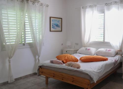 a bedroom with a bed with orange pillows and windows at חלום בגורן -יחידת אירוח in Metulla