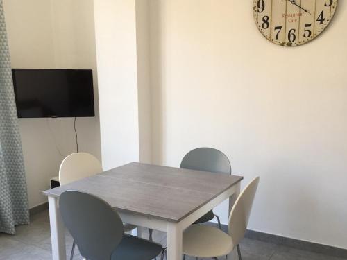 a dining room table with chairs and a clock on the wall at Ernella in Bastia