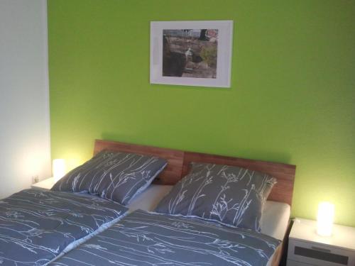 ein Schlafzimmer mit einer grünen Wand und einem Bett mit zwei Kissen in der Unterkunft Mary´s Ferienwohnung in Kevelaer