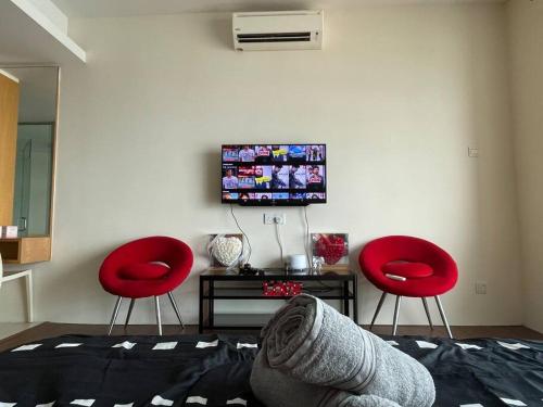 ein Wohnzimmer mit 2 roten Stühlen und einem TV in der Unterkunft Private Jacuzzi Luxury Suite at KL City 178 in Kuala Lumpur