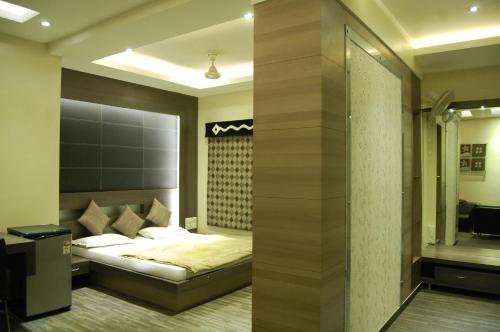 a bedroom with a bed and a walk in shower at Hotel Purva in Indore
