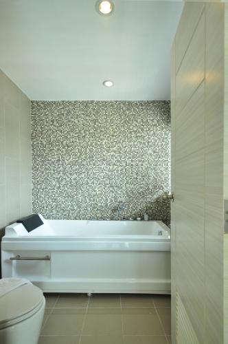 a bathroom with a bath tub and a toilet at The AIM Patong Hotel in Patong Beach