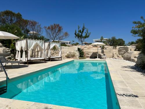 una piscina con agua azul y sombrillas en Masseria Gelsi, en Torre Chianca