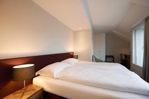a bedroom with a large white bed and a window at Parkhotel Wallberg in Volketswil