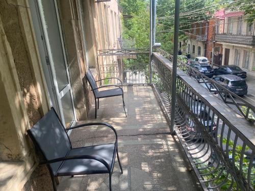 two chairs sitting on a balcony looking out onto a street at Hotel 1887 in Kutaisi