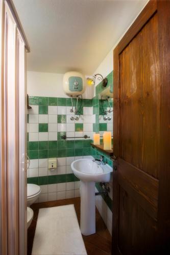 a green and white bathroom with a sink and a toilet at Antico Borgo in Galtellì