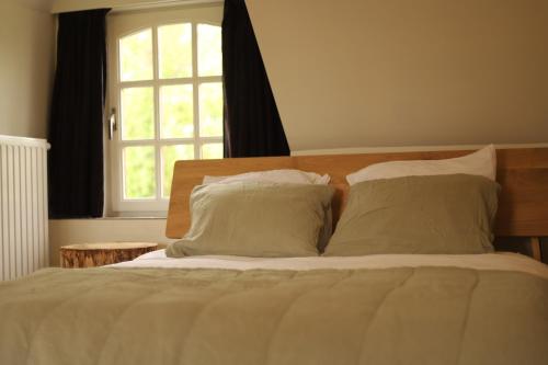 a bed with pillows and a window in a bedroom at Zee-van-Tijd in Oudenburg
