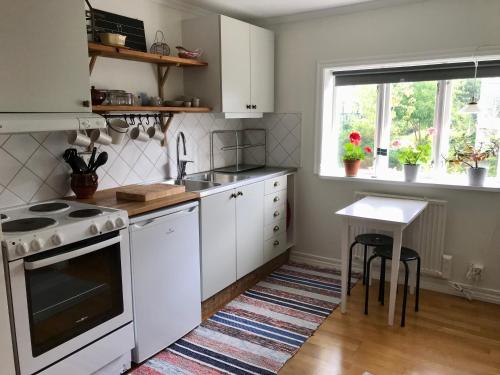 cocina con electrodomésticos blancos, mesa y ventana en Hatty's Guesthouse, en Motala