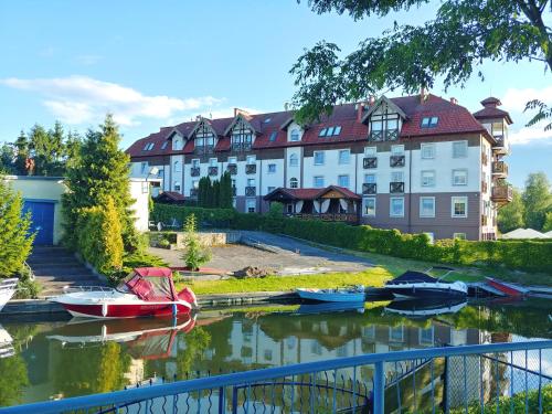 a group of boats in the water in front of a building at Apartament Żeglarski Vęgoria Deluxe z widokiem na Port in Węgorzewo