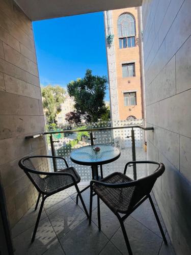 d'un balcon avec une table, deux chaises et une fenêtre. dans l'établissement A 102, apartments in the heart of the jewish quarter, à Budapest