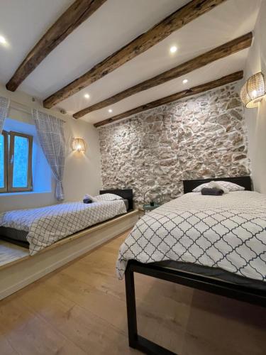 1 Schlafzimmer mit 2 Betten und einer Steinmauer in der Unterkunft Bell Tower House in Novi Vinodolski