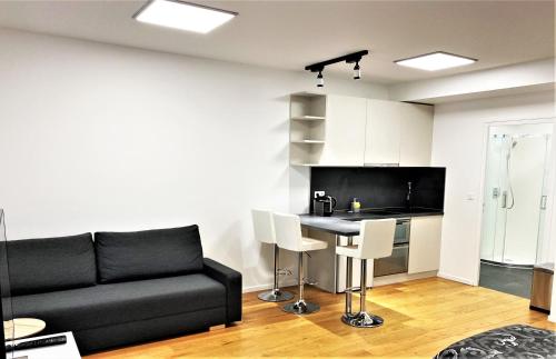 a living room with a black couch and a kitchen at Studio de standing in Malakoff
