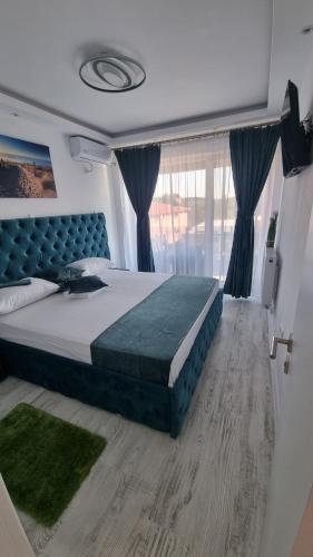 een slaapkamer met een groot bed met een blauw hoofdeinde bij Apartament Alina Sunrise in Saturn