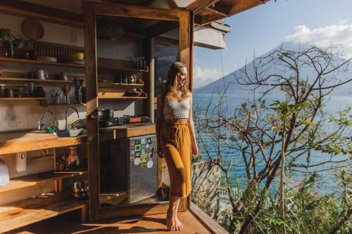 a woman standing in a kitchen looking out a window at Baraka Atitlán in San Marcos La Laguna