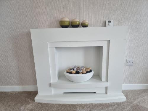 a white fireplace with a bowl of rocks and vases at Luxury 2-Bed Lodge in Routh HotTub & Pet Friendly in Routh