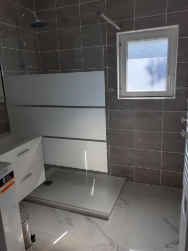 een badkamer met een douche, een wastafel en een raam bij la bonne tuile 