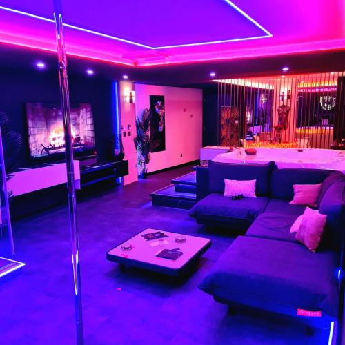 a living room with purple lighting and a couch at LES SECRETS ROOMS, LOVE ROOM DE LUXE AVEC JACUZZI in Rivesaltes