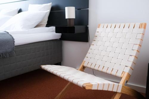 una silla junto a una cama en una habitación en Upea studioasunto historiallisella Hangon Asemalla, en Hanko