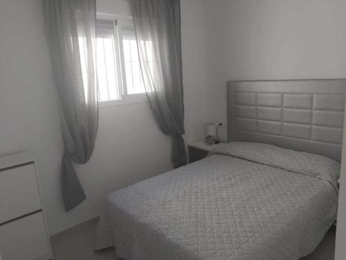 a white bedroom with a bed and a window at Casa totalmente nueva a 50 metros de la playa in El Palmar