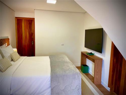 a bedroom with a bed and a flat screen tv at Casa Três Rios - Campos do Jordão in Campos do Jordão