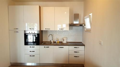 a kitchen with white cabinets and a sink at Apartment Maya 2 in Marusici 