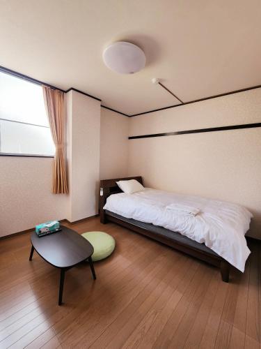 a bedroom with a bed and a table and a window at Minshuku Urbanly in Matsumoto