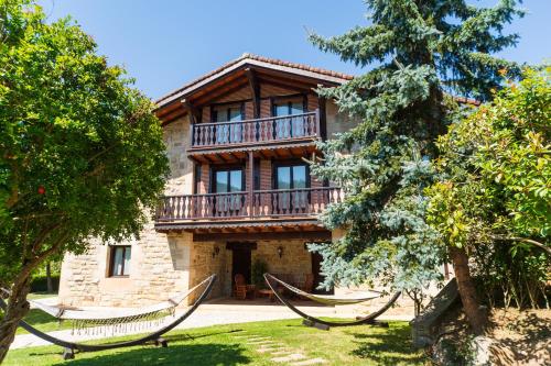 a house with a balcony and hammocks in front of it at VILLA DOLARETXE by Urdaibai Rentals in Bilbao