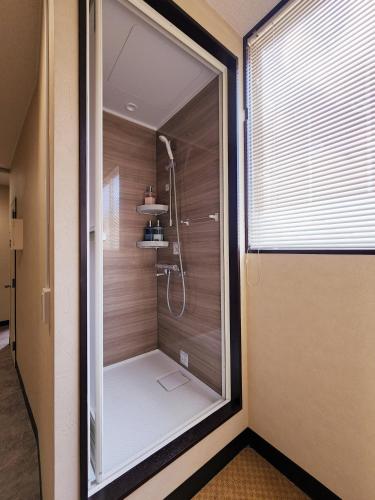 a walk in shower in a bathroom with a window at Minshuku Urbanly in Matsumoto